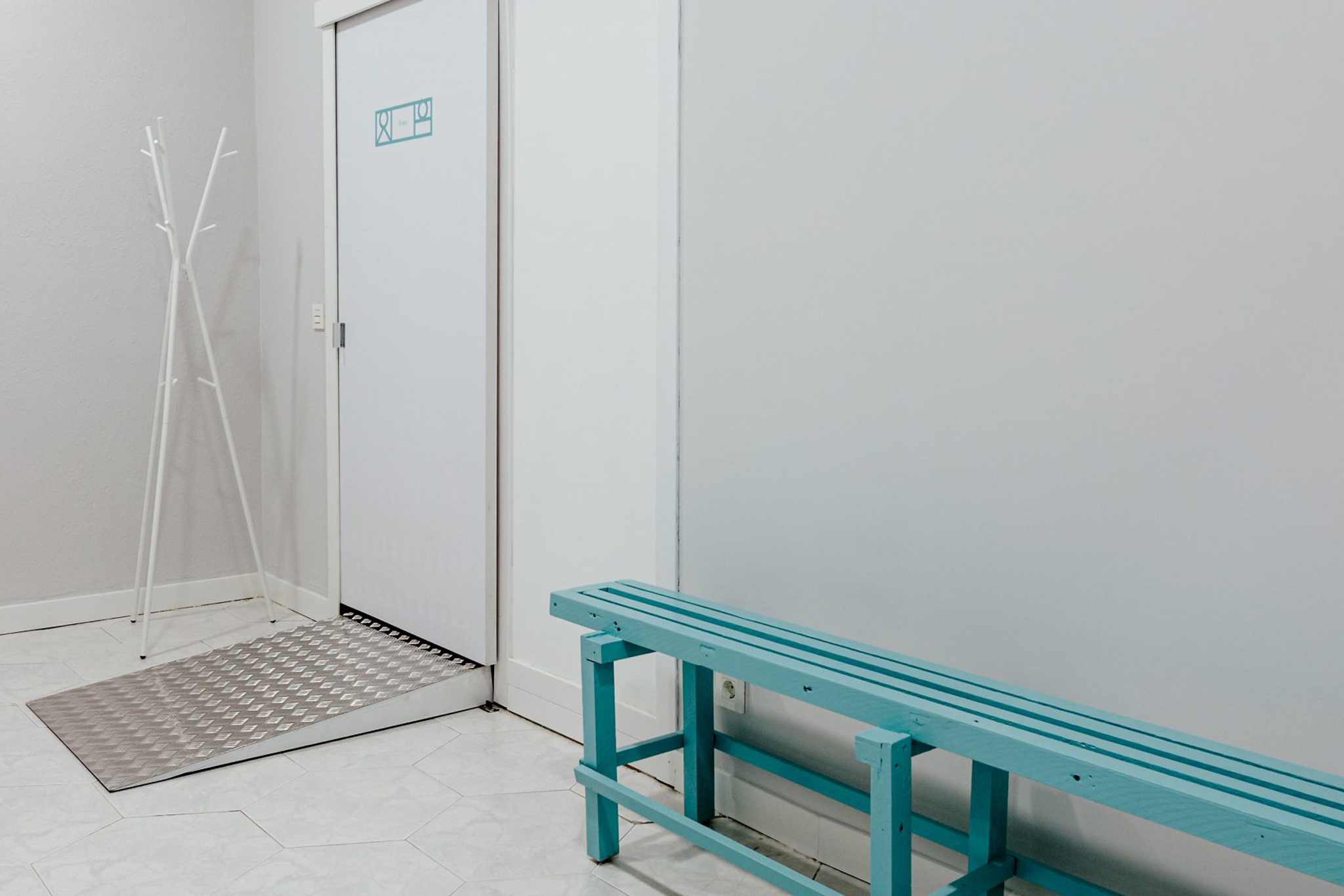 Imagen banco junto a la pared y puerta accesible